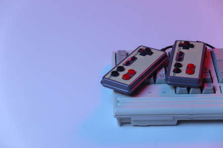 Old pc keyboard with gamepads in pink blue gradient neon, holographic light. retro wavesの写真素材