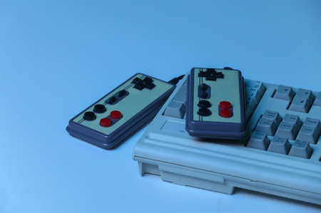 Old pc keyboard with gamepads in blue holographic light. retro waves