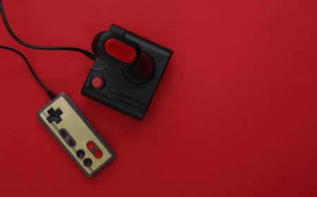 Retro joystick and gamepad on red background. Gaming, video game competition. top view