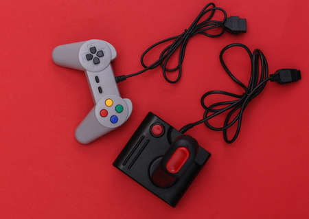 Wired retro gamepad and joystick with wound cable on red background. video game, gaming. top viewの写真素材