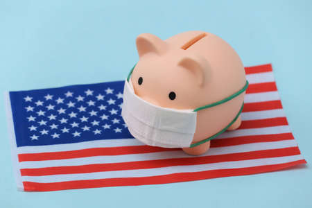Piggy bank in a medical mask with the USA flag on a blue background. Pandemic covid-19の写真素材