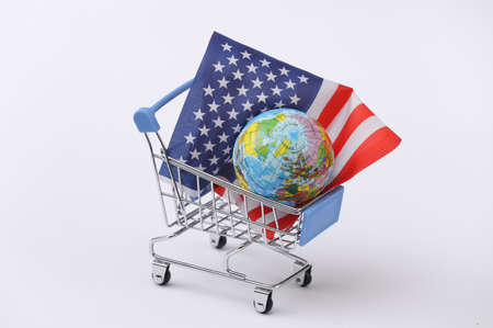 Mini supermarket trolley with USA flag, globe on white background.