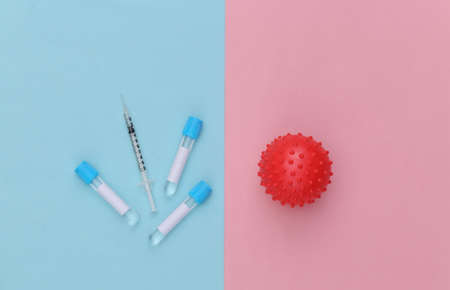 Medical test tubes with syringe, virus strain model on blue pink pastel background. vaccination. top...