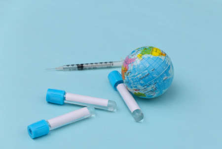 Globe, Medical test tubes with syringe on blue background. global vaccination.