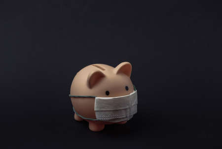 Piggy bank with medical mask on black background. economic disease. financial crisis.の写真素材