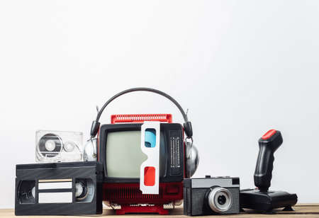 Retro portable mini tv set with headphones, 3d glasses, camera, joystick, audio and video cassette on white background. Attributes 80s, retro styleの写真素材