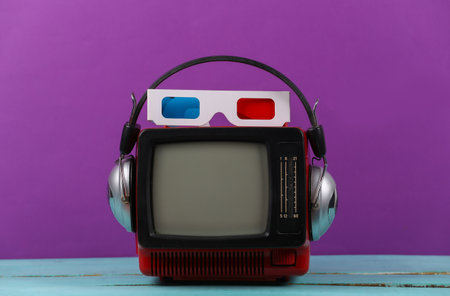 Red retro old portable mini tv set with headphones, 3d glasses on purple background. Attributes 80s, retro styleの写真素材