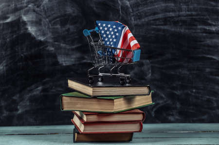 Usa flag in shopping trolley on books stack. blackboard backgroundの写真素材