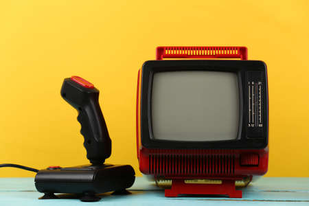 retrogaming. Video game competition. Old TV with joystick on yellow background. Attributes 80sの写真素材
