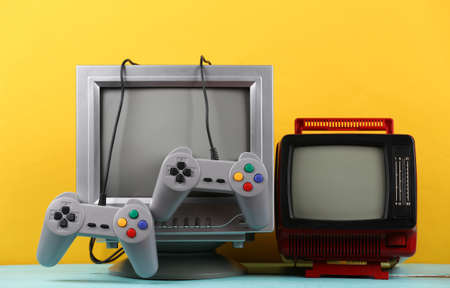 retrogaming. Video game competition. Old TVs with joysticks and gamepads on yellow background. Attributes 80sの写真素材