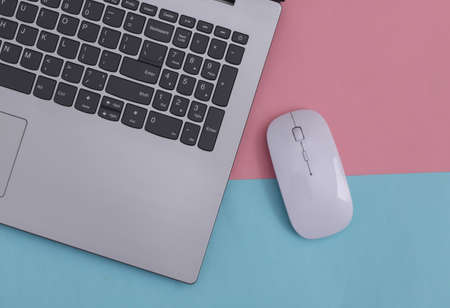 Laptop with pc mouse on pink blue pastel background. online workspace. remote work. studio shot. top...