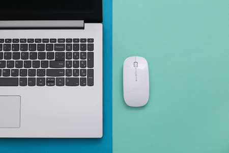 Laptop with pc mouse on a colored paper background. online workspace. remote work. studio shot. top view. flat layの写真素材