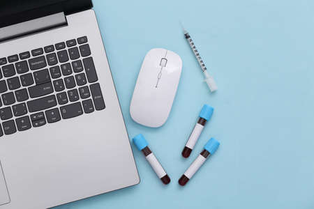 Workspace of doctor (laboratory worker). Notebook test tubes and syringe on blue background. top...
