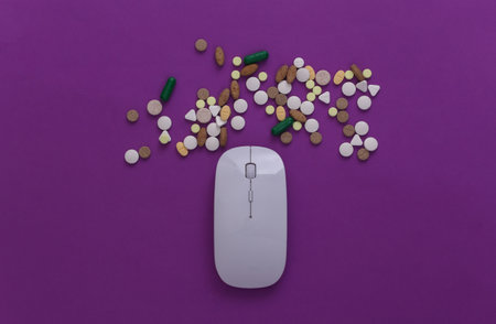 Pc mouse with pills on purple background. top view. flat layの写真素材