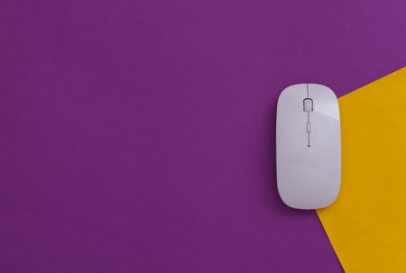 White modern wireless pc mouse on purple yellow background. top viewの写真素材