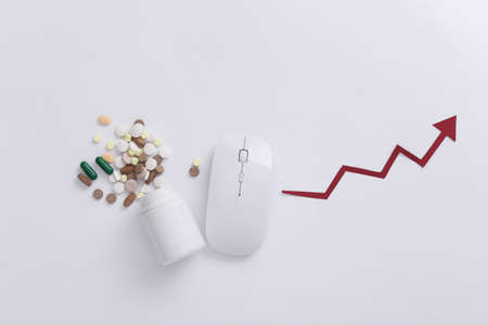 Pc mouse with bottle pills, rising arrow on white background. top view. flat layの写真素材