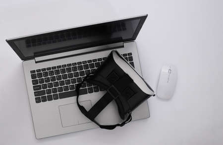Laptop with VR glasses on white background. The virtual reality. Modern gadgets. top view. flat layの写真素材