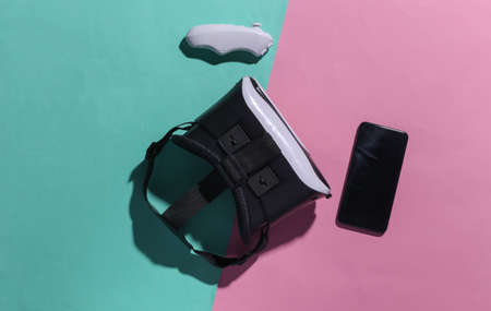 Virtual reality headset with joystick and smartphone on pink blue pastel background with shadow. top view. Fly lay. minimalismの写真素材