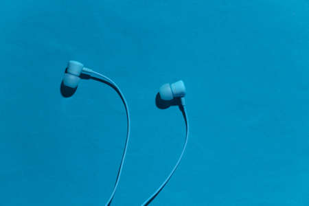 Trendy wired earphones on a blue background with shadow. top viewの写真素材