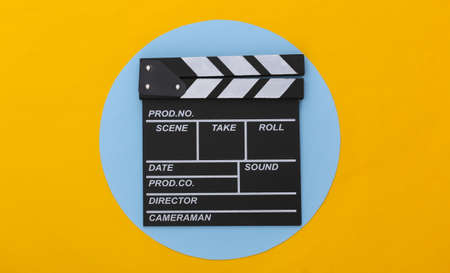 Movie clapper board on yellow blue background. Filmmaking, Movie production, Entertainment industry. top viewの写真素材