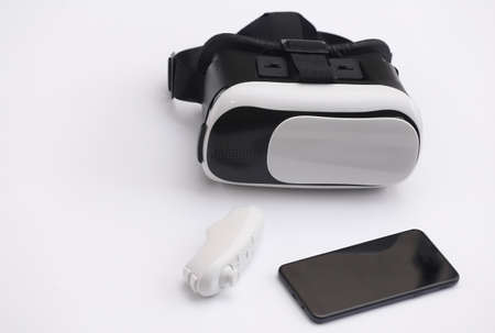 Virtual reality headset with joystick and smartphone on white background. Modern gadgets