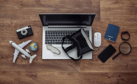 Flat lay composition of laptop and vr headset, travel accessories on a wooden floor. Virtual Tourism. top view.の写真素材