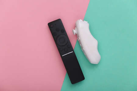 TV remote with a joystick on pink blue pastel background. entertainment. top view