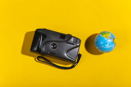 travel concept. Camera with a globe on yellow background with shadow. top viewの写真素材