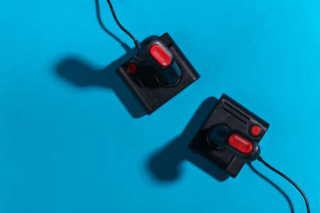Two retro joysticks on a blue background with a shadow. retro gaming. top view