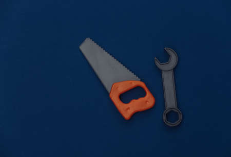 Toy saw and wrench on classic blue background. Color 2020の写真素材