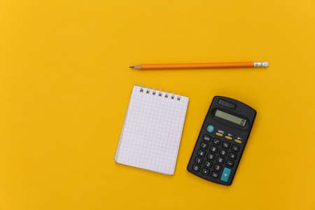 Notebook with pencil, calculator on yellow background. top viewの写真素材