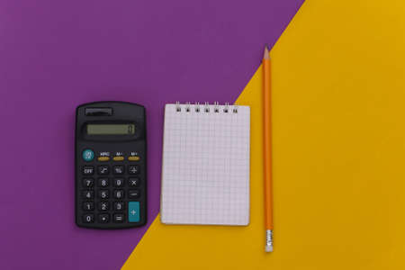 Notebook with pencil, calculator on purple yellow background. top viewの写真素材
