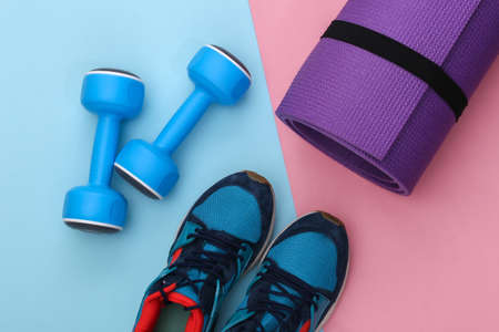 Sports shoes (sneakers) and blue dumbbells, fitness mat on pink blue background. Healthy lifestyle, fitness training. top viewの写真素材