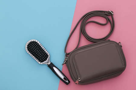 Fashionable leather bag and hair brush on pink blue pastel background. top view.の写真素材