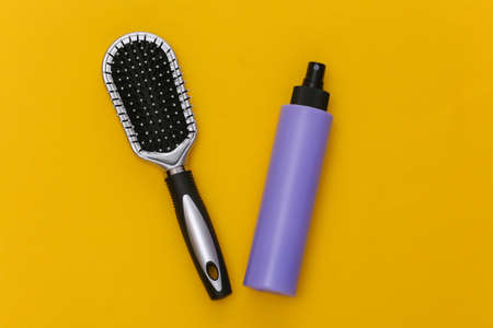 Bottle of hairspray, hair brush on yellow background. top viewの写真素材