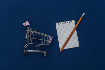 shopping list. Shopping trolley with notebook and pencil on classic blue background. Color 2020の写真素材