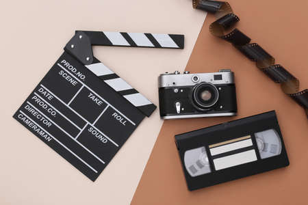Movie clapper board, video cassette, film tape, camera on beige brown background. Filmmaking, Movie production, Entertainment industry. top viewの写真素材