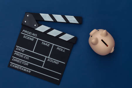 Movie clapper board and piggy bank on classic blue background. Filmmaking, Movie budget, Entertainment industry. Color 2020の写真素材