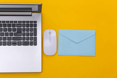 online payment. Laptop with pc mouse, envelope on yellow background. top view.