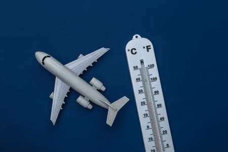 Weather thermometer with toy plane on classic blue background. Color 2020. Tiop view