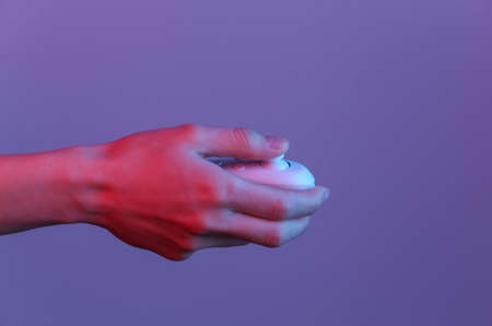 Hand holds modern joystick in blue neon light.