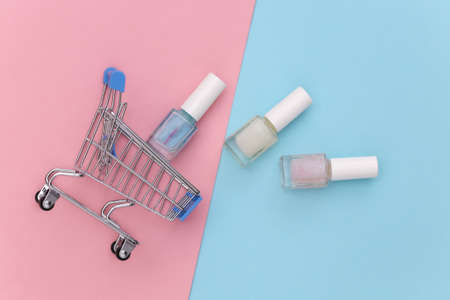 Shopping trolley with nail polish bottle on blue pink background. beauty market. top viewの写真素材