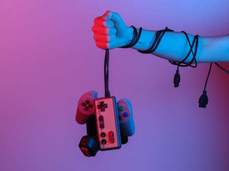 Hands holding retro joystick by cable in blue-red neon gradient light. old gaming. 80s retro wave. minimalismの写真素材