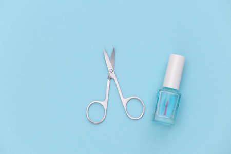 Nail polish bottle and manicure scissors on blue background. beauty concept. top viewの写真素材