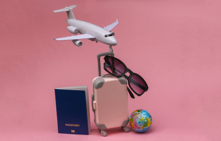 Air travel concept. Travel suitcase, air plane, globe, passport and sunglasses on pink pastel background.の写真素材