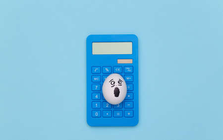 Puzzled egg faces and calculator on a blue background. top viewの写真素材