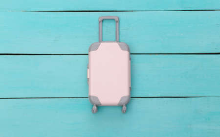 Flat lay vacation holiday and travel planning concept. Mini plastic travel suitcase on blue wooden background. top viewの写真素材