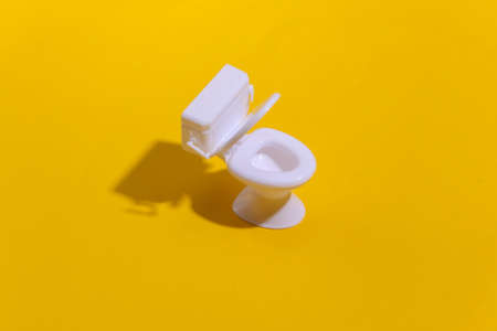Mini white toilet on yellow background with deep shadow. minimalism.の写真素材