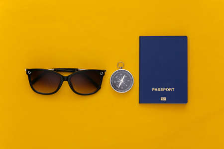 Compass and sunglasses, passport on yellow background. top view. Minimalism travel concept. flat lay