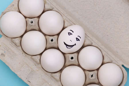 Happy Egg face in egg tray on blue background. top view